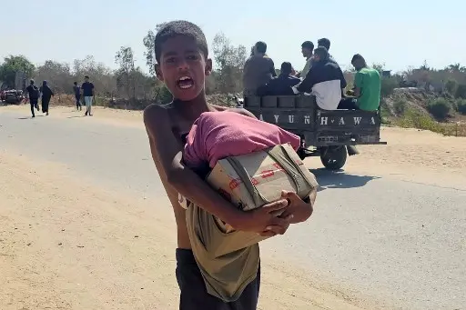 A boy walks with humanitarian aid relief packages